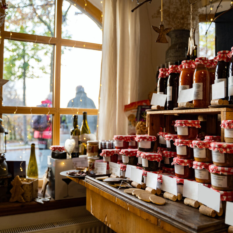 Glass jars with large variety of natural homemade country jams and honey on counter of cozy shop