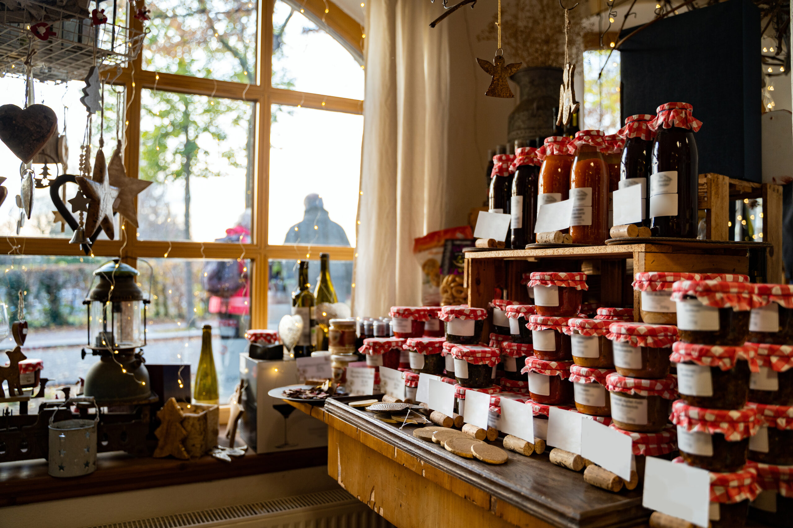 Glass jars with large variety of natural homemade country jams and honey on counter of cozy shop