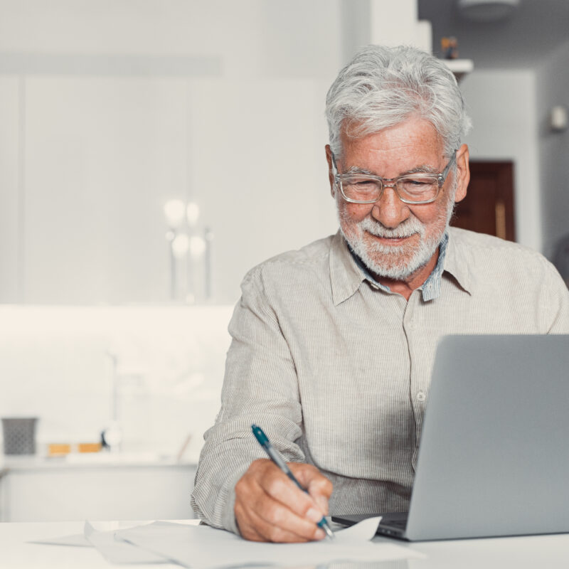 Concentrated senior male in glasses work on laptop from home office