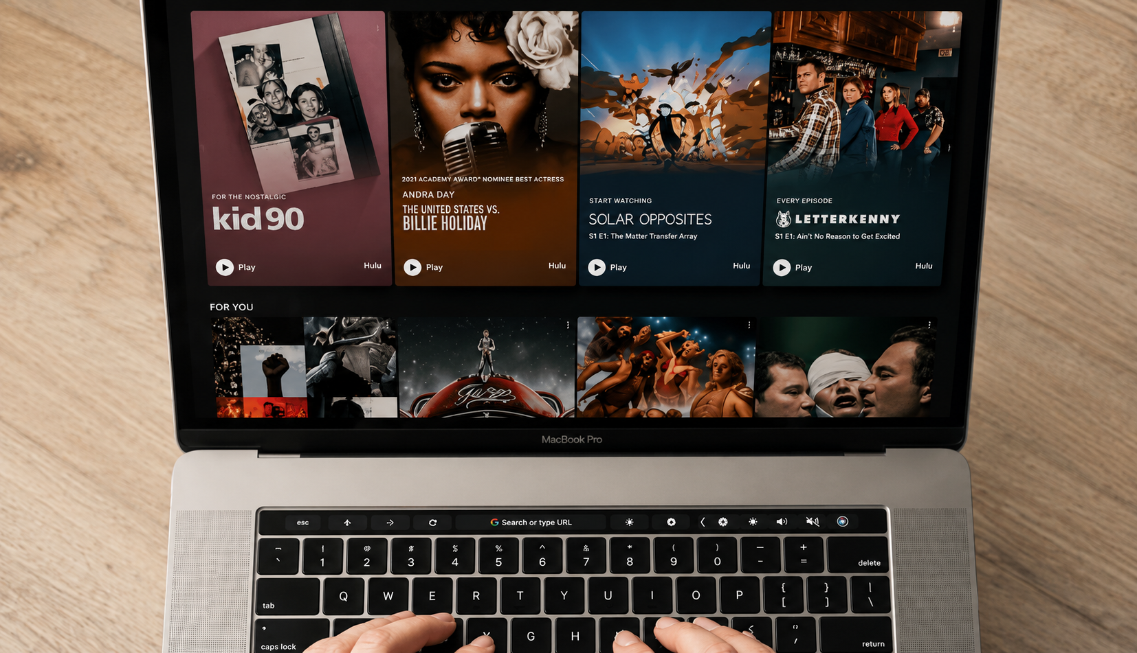 person using a laptop displaying a streaming platform interface with featured TV shows and movies in a modern home setting