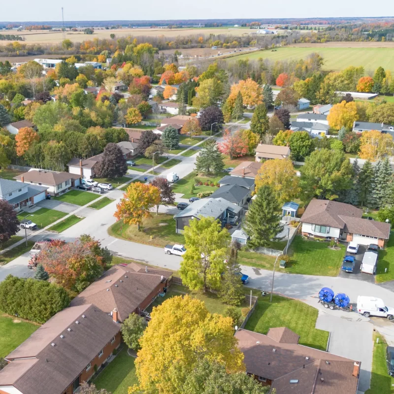 Aerial view of a rural neighborhood with scattered houses, tree-lined properties, and long driveways connecting homes to the road.