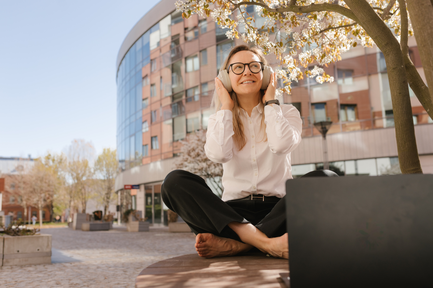 Professional woman working remotely outdoors using technology with headphone on