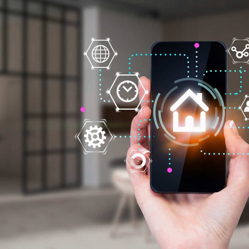 Hand of woman holding smartphone with glowing smart home interface