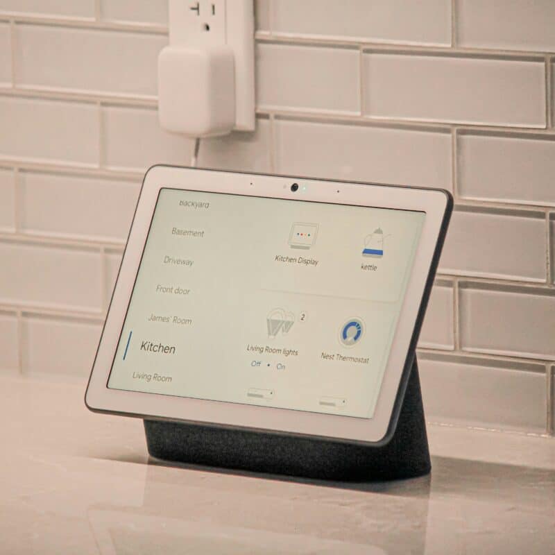 Tablet displaying smart home controls for kitchen lighting, kettle, and thermostat on a kitchen counter