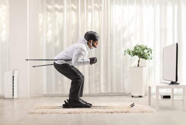 Profile shot of a man skiing at home in a living room in front of tv