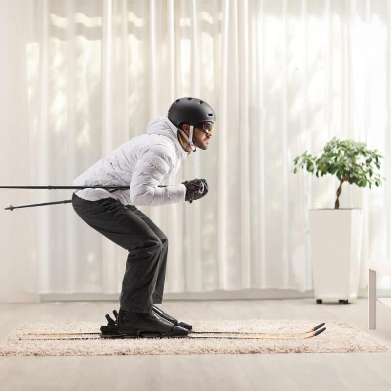 Profile shot of a man skiing at home in a living room in front of tv