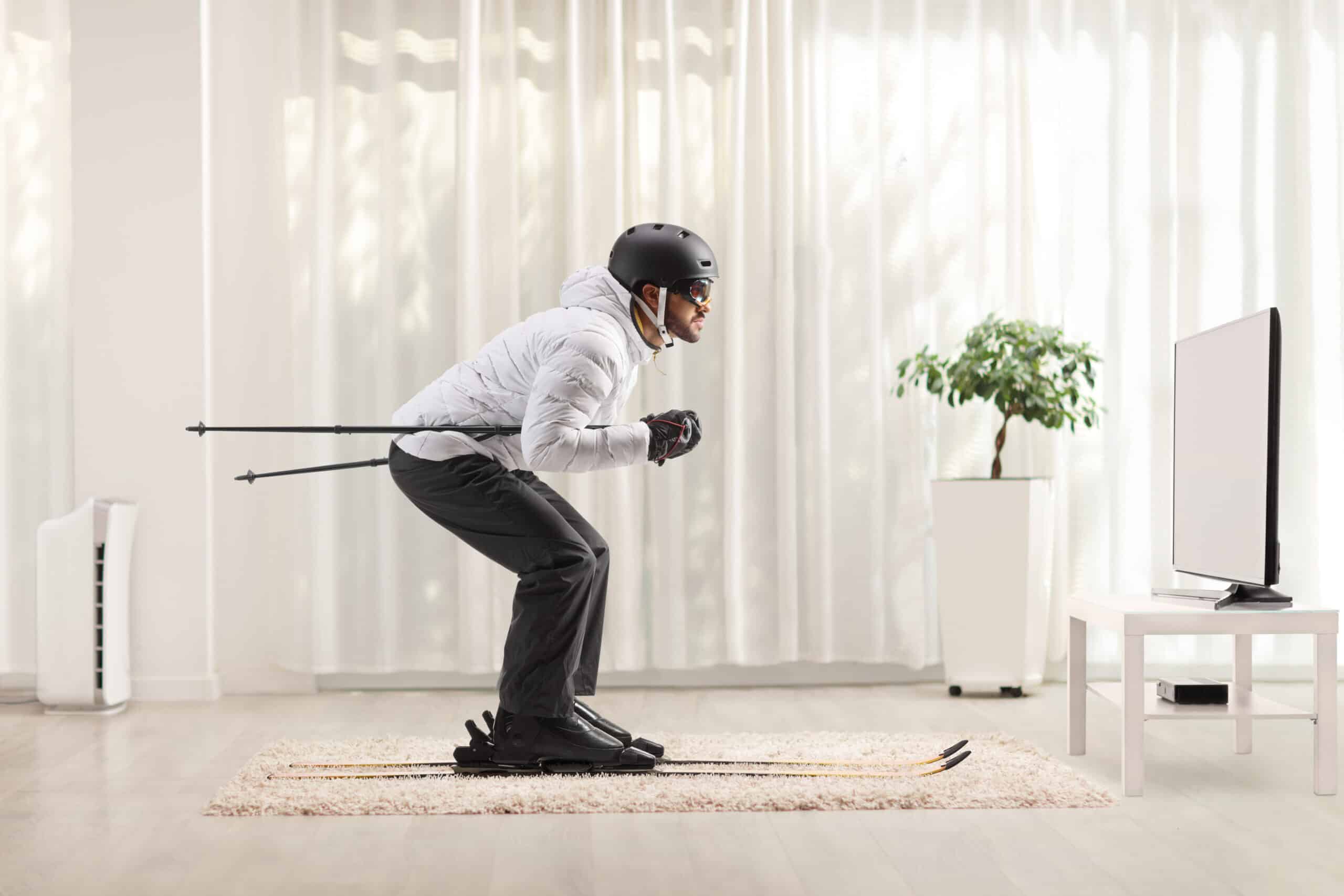 Profile shot of a man skiing at home in a living room in front of tv
