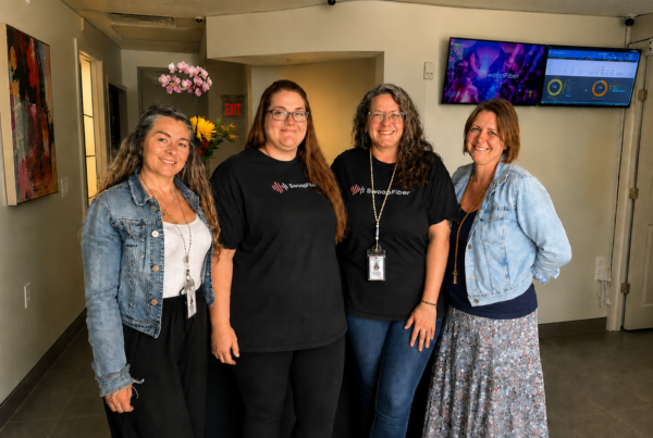 Four SwoopFiber Staff memebers standing in the storefront smiling