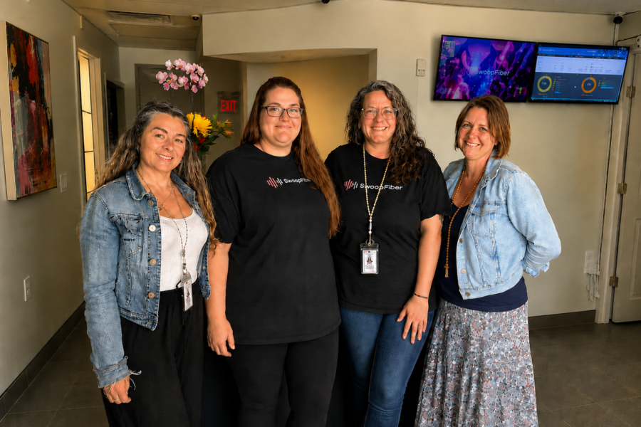 Four SwoopFiber Staff memebers standing in the storefront smiling